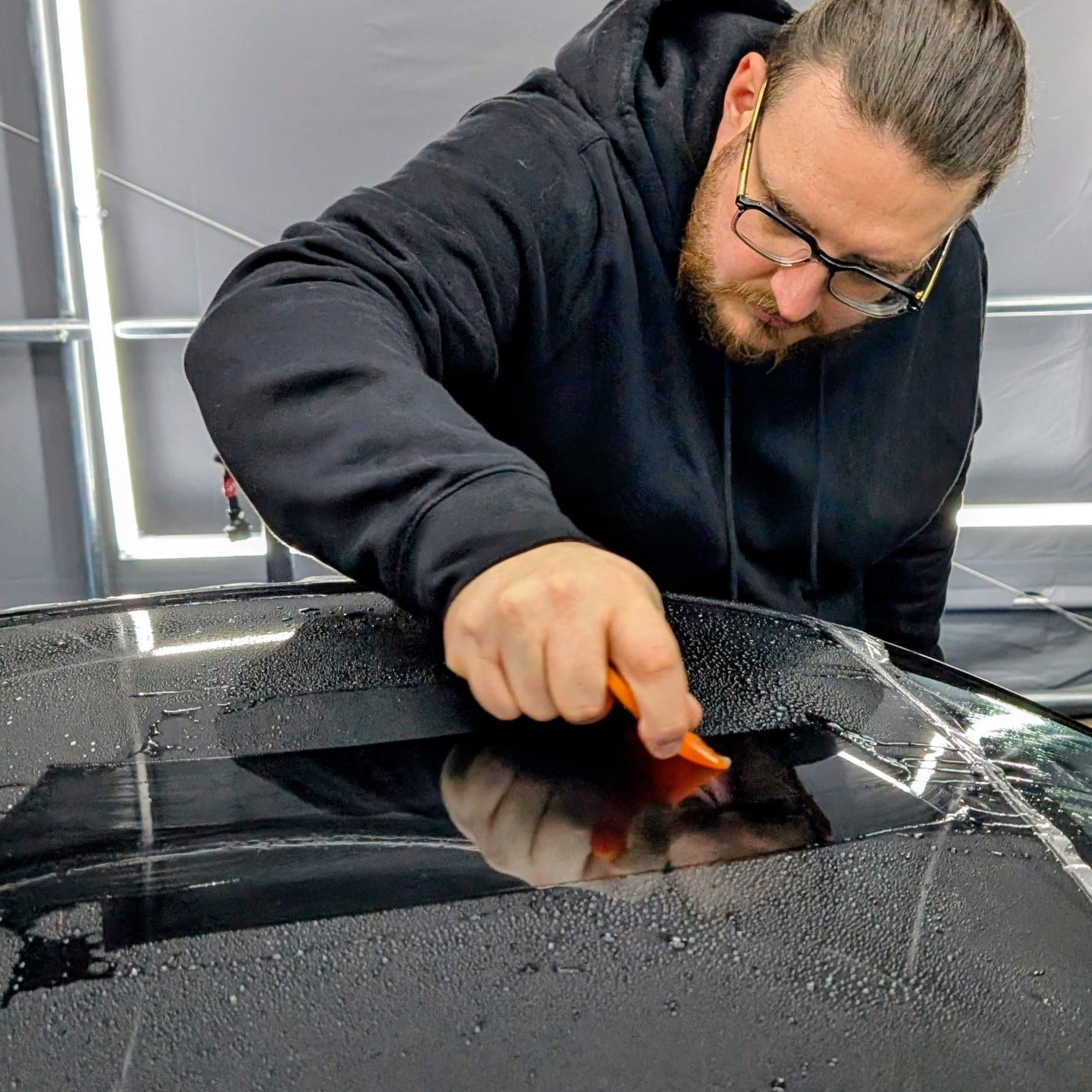 Dimitri en train de poser un film de protection PPF sur un véhicule dans l'atelier MajesticAuto